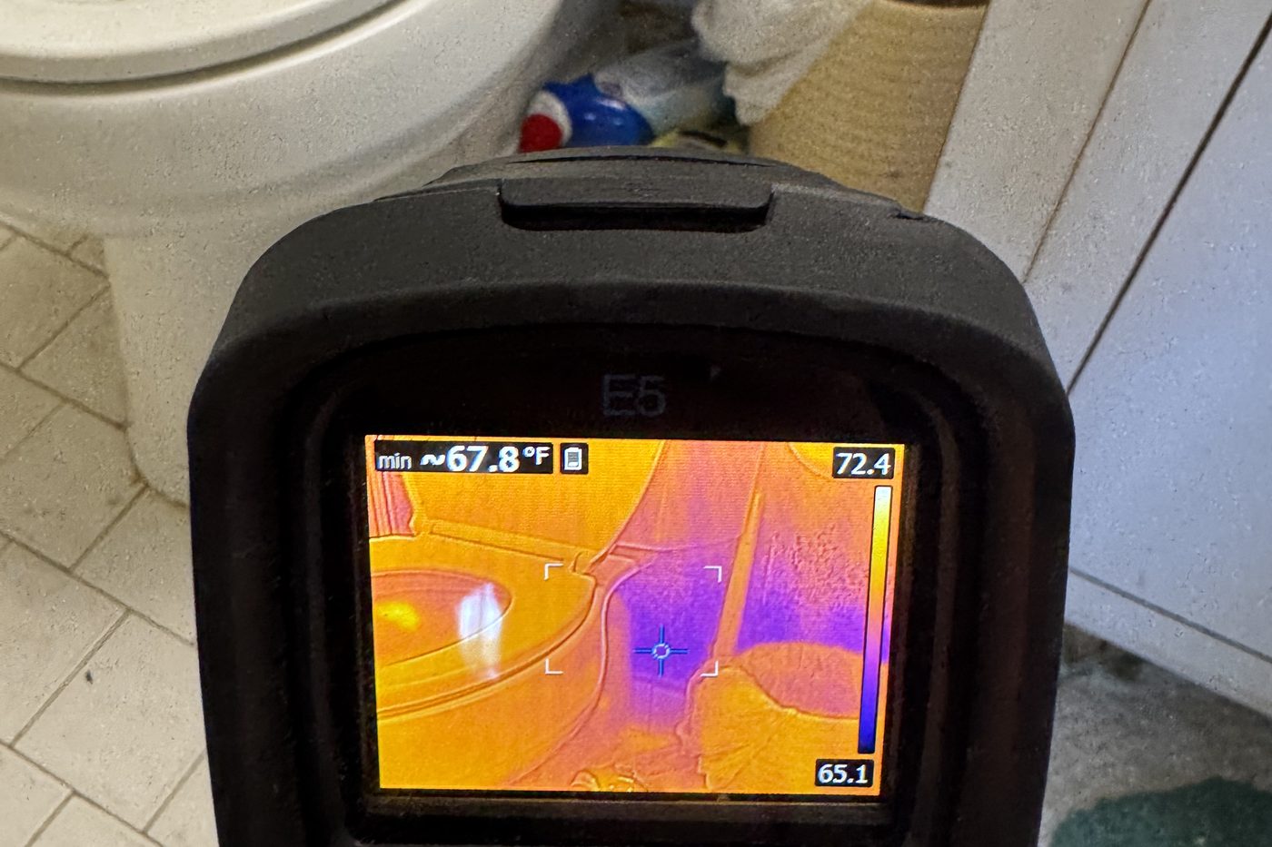Thermal scan of a leaking toilet base showing water spread across bathroom tile